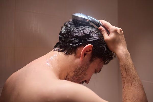 uomo girato di spalle che si lava i capelli - costi trapianto capelli