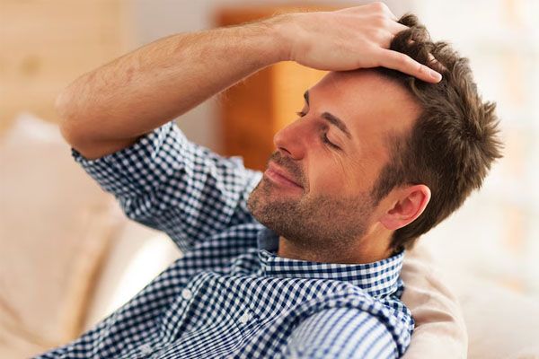 Uomo maturo seduto rilassato che si sistema i capelli con la mano