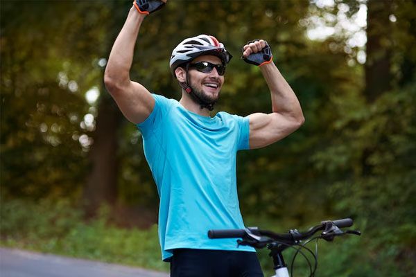 ciclista che festeggia andando in bicicletta con le mani alzate - Sport dopo il trapianto capelli