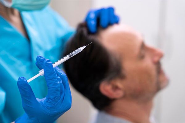 primo piano della mano del medico che tiene la siringa - cliniche trapianto capelli Milano più innovative