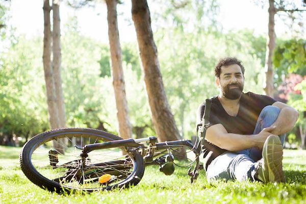 uomo seduto al parco che si riposa con la sua bicicletta a lato - migliori cliniche trapianto capelli Italia