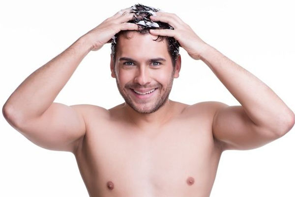 Inquadratura frontale di un uomo sorridente che si lava i capelli