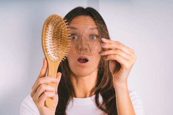 La donna guarda sorpresa i capelli impigliati nella sua spazzola
